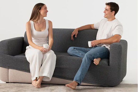 Grijze bank met volledige bankhoes waarop man en vrouw zitten