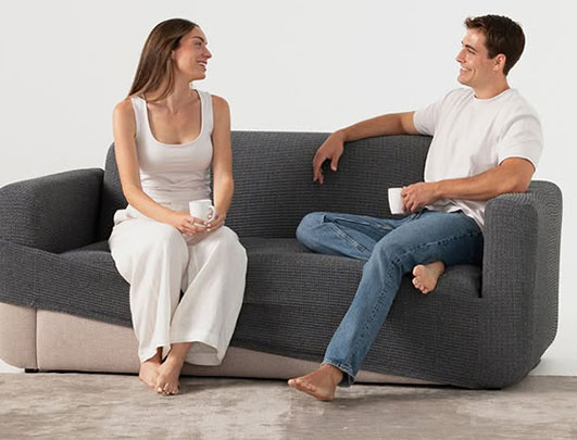 Grijze bank met volledige bankhoes waarop man en vrouw zitten