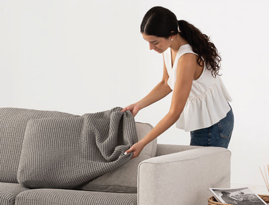 Bankhoes op maat wordt strak over de rugleuning van een hoekbank geplaatst