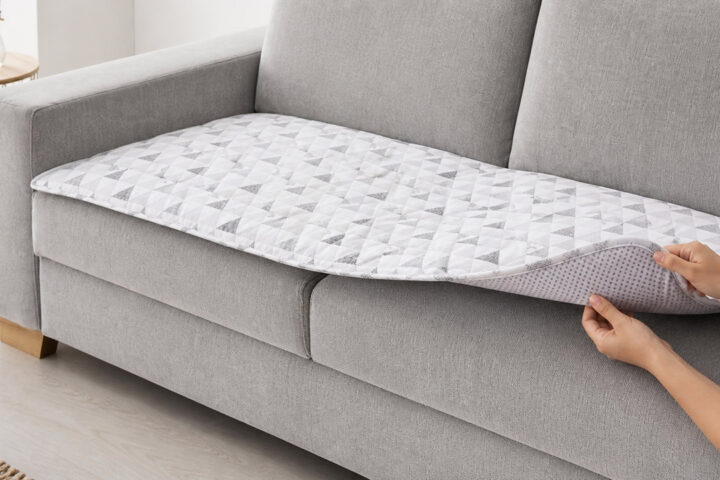 Handen tonen de antislip onderzijde van een banktopper op een grijze bank